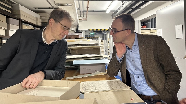 Direktor der Landesbibliothek Martin Lätzel (links) und Minister für Digitalisierung Dirk Schrödter (rechts) schauen auf Texte der Bibliothek.