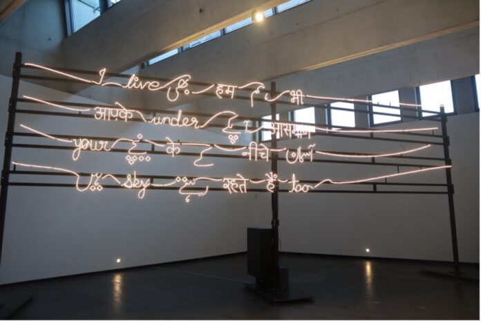 Leuchtende Schreibschriftworte, die abwechselnd auf English, Hindi und Urdu 